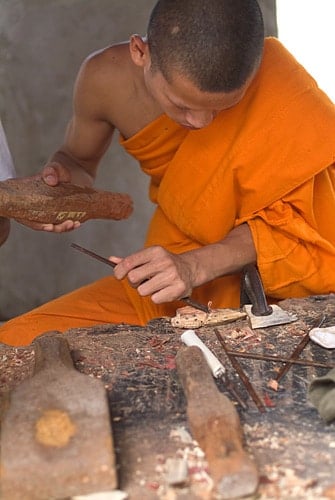 Monje tallando imágenes de Buda sobre madera