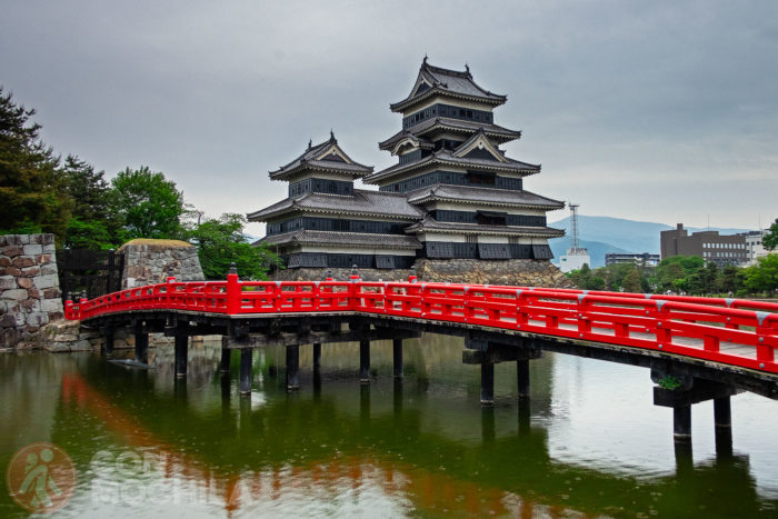 El castillo de Matsumoto y el brillante puente rojo que cruza el estanque